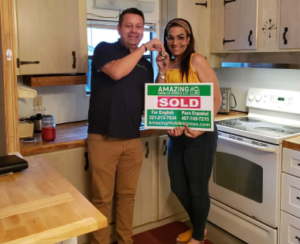 sales agent with lady holding a sold sign in the kitchen of her new mobile home