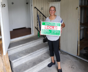 lady holding sold sign in front of the mobile home